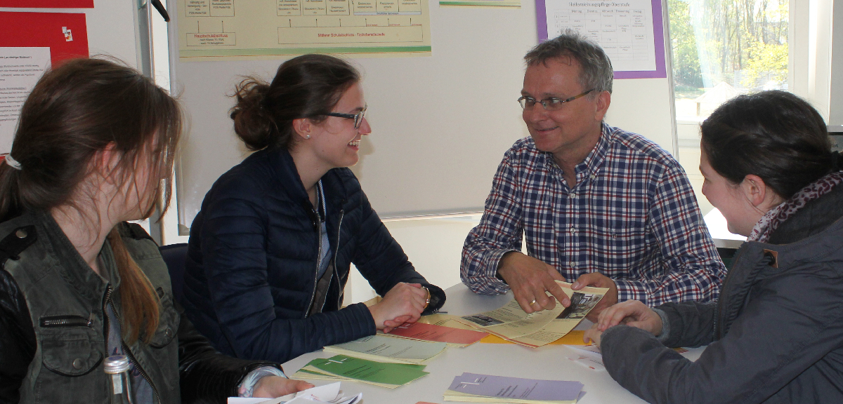 Beratungsgespräch an der Liebfrauenschule: eine Lehrkraft berät Schülerinnen mit Informationsmaterial